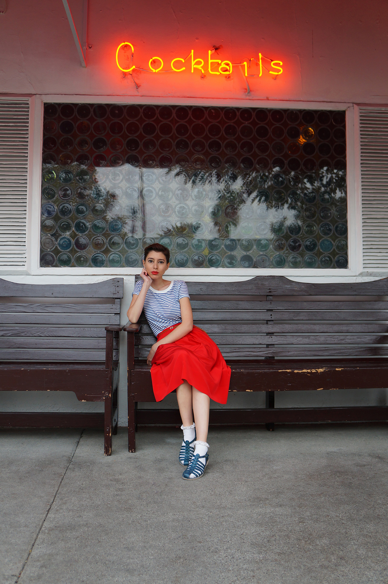 Woman wearing a red skirt in font of cocktail bar